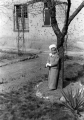 Hungary, Budapest XI., a felvétel a Károli Gáspár tér 9. számú ház kertjében készült., 1955, Martin Kornél, Budapest, girl, headscarf, gloves, bullet hole, garden, Fortepan #196881