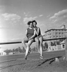 Magyarország, Budapest X., Maglódi út 4. sportpálya, a Kinizsi Sörgyár női röplabdacsapat tagjai, háttérben a Növényolaj és Szappangyár., 1955, Keveházi János, Budapest, képarány: négyzetes, mosoly, nő, sportoló, korláton ülni, Fortepan #197199