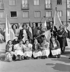 Magyarország, Budapest XIV., Stefánia (Vorosilov) út, május 1-i felvonulás résztvevői a 41. számú épület előtt., 1955, Keveházi János, Budapest, nők, csoportkép, képarány: négyzetes, zászló, kötény, guggolás, békegalamb, Fortepan #197258