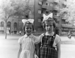 Hungary, Budapest VIII., II. János Pál pápa (Köztársaság) tér, háttérben a 17. és 16. számú ház., 1957, Keveházi János, Budapest, hairdo, girls, ribbon, apron dress, necklace, Fortepan #197495