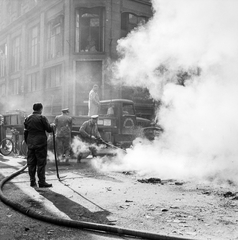 Magyarország, Budapest V., Kossuth Lajos utca, elégetett könyvek maradványait oltják a Magyar Szovjet Társaság Országos Központja előtt, háttérben a Magyar utca sarkán álló ház., 1956, ETH Zürich, Comet Photo AG/Jack Metzger, teherautó, munkaruha, munkás, füst, tányérsapka, tűzoltó fecskendő, Budapest, autón állni, képarány: négyzetes, Fortepan #197793