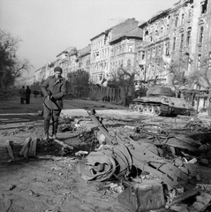 Magyarország, Budapest VIII., József körút a Corvin (Kisfaludy) köznél. Harcképtelenné tett T-34/85 harckocsi. Szemben a Práter utca - Nap utca - Baross utca közötti házsor., 1956, ETH Zürich, Comet Photo AG/Jack Metzger, utcakép, járműroncs, rom, fegyver, férfi, puska, T-34 tank, Budapest, Fortepan #197805