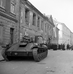 Magyarország, budai Vár, Budapest I., Úri utca 62., Prímási palota. Mindszenty József bíboros hercegprímás, esztergomi érsek felsőpetényi őrizetéből való kiszabadulása utáni rádióbeszédére várakozók., 1956, ETH Zürich, Comet Photo AG/Jack Metzger, tömeg, forradalom, utcakép, önjáró löveg, SZU-76 rohamlöveg, Budapest, épületkár, képarány: négyzetes, golyónyom, Fortepan #197811