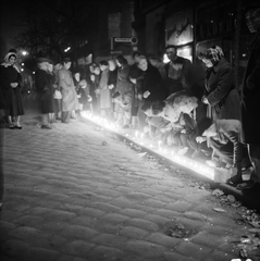 Magyarország, Budapest, megemlékezés halottak napján egy buszmegállóban, az 1956-os forradalom alatt elkövetett egyik atrocitás helyszínén., 1956, ETH Zürich, Comet Photo AG/Jack Metzger, tömeg, forradalom, gyertya, megemlékezés, éjszaka, gyász, kabát, gyertyafény, képarány: négyzetes, Fortepan #197832