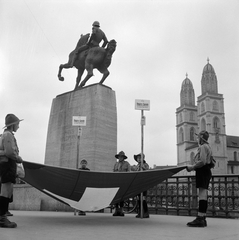 Svájc, Zürich, Stadthausquai, a háttérben jobbra a Grossmünster (Nagykatedrális). Hans Waldmann lovasszobra (Hermann Haller, 1937.)., 1956, ETH Zürich, Comet Photo AG/Max A. Wyss, képarány: négyzetes, adománygyűjtés, ponyva, cserkész, lovas szobor, Fortepan #197844