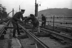 Magyarország, Budapest V., Dunakorzó, a villamospálya javítása. Háttérben a lerombolt Erzsébet híd pesti hídfője és a Gellért-hegy., 1956, Bauer Sándor, Budapest, katona, sínpálya, munkás, talpfa, tányérsapka, Fortepan #199449