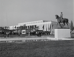 Magyarország, Budapest X., Mezőgazdasági Kiállítás az Albertirsai úti vásár területén. Jobbra Szabó Iván szobra, Sportlovasnő (1954), később Kiskunhalasra került. Háttérben a Lóversenypálya tribünje., 1954, Kotnyek Antal, Ráth Károly, lovas szobor, lovassport, Budapest, Fortepan #21771