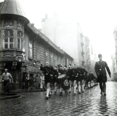 Magyarország, Budapest I., Fő utca a Pala utcánál, a magyarországi nyaralásra érkező német gyerekek egyik csoportjának, a Hitlerjugend tagjainak felvonulása., 1942, Mihályi Balázs, Budapest, hitlerjugend, katonazenekar, sarokerkély, dob, trombita, horogkereszt, Fortepan #217804