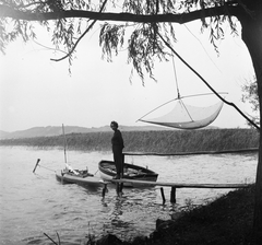 Magyarország,Balaton, Szántód, stég a Balaton partjánál, háttérben a nádas felett a Tihanyi-félsziget látható., 1956, Kotnyek Antal, Ráth Károly, portré, vitorláshajó, csónak, stég, nádas, hölgy, melegítő, halászháló, Fortepan #21902