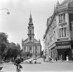 Hungary, Kecskemét, Kossuth tér, Római Katolikus Nagytemplom (Öregtemplom)., 1955, Gyöngyi, bicycle, church, sign-board, neon sign, lamp post, Baroque-style, cobblestones, Catholic Church, automobile, savings bank, church clock, Gáspár Oswald-design, Fortepan #2206