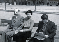 Magyarország, Budapest V., Széchenyi rakpart, háttérben a Balassi Bálint (Személynök) utca épületei a Stollár Béla utca torkolatánál., 1953, Jakucs János/Czeisler család, Budapest, pad, életkép, olvasás, újság, karóra, nyakkendő, villamos, emberpár, úriember, Fortepan #221486