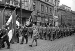 Magyarország, Budapest VIII., Baross tér, repülősök a május 1-i felvonuláson a 6. és a 4-5. számú ház előtt, jobbról az 1., 2. és 3. számú ház. A kettő között balra kezdődik a Fiumei út., 1953, Nasztanovics Ferenc, Budapest, cégtábla, egyenruha, zászló, felvonulás, Fortepan #222192