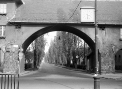 Magyarország, Budapest XIX., Wekerletelep, Kós Károly (Petőfi) tér, Kós-kapu a Hungária út felé nézve., 1982, Bekker Sándor, óra, kapu, utcakép, boltív, jelzőtábla, kapualj, Budapest, Kós Károly-terv, Fortepan #22747