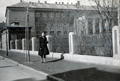 Magyarország, Budapest IV., Nyár utca, jobbra a Tanoda (Ferenc József) tér, a háttérben a Pozsonyi utca túloldalán a Magyar Királyi Állami Könyves Kálmán Gimnázium., 1938, Vízkelety László, Budapest, kerítés, facsemete, lány, kabát, egyensapka, Fortepan #227547