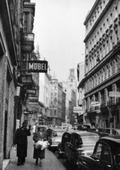 Ausztria, Bécs, Zollergasse a Mariahilfer Strasse felől. A távolban a Mondscheingasse sarkán álló egykori posta- és távíróközpont óratornya látszik., 1954, Stuber Andrea, utcakép, cégtábla, Fortepan #229654