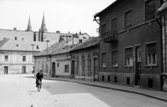 Szlovákia, Komárom, Király püspök utca, szemben a Lúdpiac tér (Tržničné Námestie), háttérben a Szent András-templom tornyai., 1954, Stuber Andrea, utcakép, templomtorony, lakóház, kerékpár, Fortepan #229670