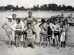 Magyarország, Budapest II., Duna strandfürdő az Újlaki rakparton a Sajka utcánál, szemben a Margit-sziget., 1931, Schaffer Anikó, csípőre tett kéz, csoportkép, fürdőruha, folyópart, fürdőtrikó, nyakban ülés, fürdősapka, homok, Budapest, Fortepan #229914