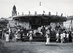 Hungary, Budapest IX., Haller utcai vásártér, háttérben balra a Páli Szent Vince-templom., 1940, Bor Dezső, Best of, kids, women, fair, men, carousel, Budapest, Fortepan #231558