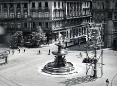 Hungary, Budapest VIII., Kálvin tér, Danubius-kút. Balra a Baross utcánál az Első Pesti Hazai Takarékpénztár épülete, jobbra az Üllői út torkolata., 1940, Bor Dezső, scaffolding, Fountain, pulpit for police officers, intersection, tram, bicycle, Budapest, Fortepan #231589