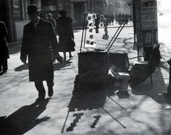 Magyarország, Budapest IX., Ferenc körút, a felvétel a Tompa utcánál készült, jobbra a távolban a Boráros tér, a Petőfi (Horthy Miklós) híd felhajtója., 1940, Bor Dezső, Best of, fény-árnyék, utcakép, járókelő, könyvárus, hirdetőoszlop, Budapest, Fortepan #231594