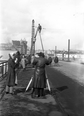 Magyarország, Budapest VI.,Budapest XIII., Ferdinánd (Élmunkás) híd, a felvétel a trolibusz felsővezetékének szerelésekor készült., 1955, FŐMTERV, Domonkos Endre, Budapest, szerelés, háttal, felsővezeték, földmérő, szintező, bőrkabát, létra, Fortepan #251015