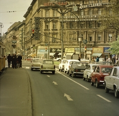 Magyarország, Budapest VI., Teréz (Lenin) körút, a Nyugati pályaudvar felé tartó villamos megállója az Oktogonnál (November 7. tér)., 1974, FŐMTERV, Domonkos Endre, színes, Édességbolt, trafik, illatszerbolt, óra-ékszer, villamosmegálló, utcakép, Trabant-márka, cégtábla, óra, életkép, Budapest, Fortepan #253501