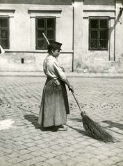 Magyarország, Budapest VIII., a Vásár utca (Rákóczi tér) és a Víg utca kereszteződése. A felvétel az I. világháború kitörése utáni mozgosítás idején, 1914. augusztus 15-én készült., 1914, Országos Széchényi Könyvtár, Müllner János, utcaseprő, nő, Budapest, seprű, kockakő, Fortepan #256219