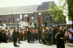 Magyarország, Budapest VII.,Budapest VIII., május 1-i felvonulók a Dózsa György út 6. számú ház előtt, háttérben a Magyar Posta Budapesti Csomagkézbesítő Üzem 1. sz. csomagkézbesítő bázisa., 1976, Tildy Istvánné, Budapest, színes, május 1, eszperantó, Fortepan #256655