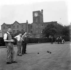 Egyesült Királyság, Salford, Dean Road 76., az 1856-ban alapított textilgyár előtt helyiek bowlingoznak (bowling green)., 1956, UWM Libraries, Harrison Forman, pipa, képarány: négyzetes, kertésznadrág, pázsit, golyó, Fortepan #258869