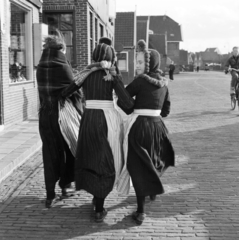 Hollandia, Volendam, népviseletbe öltözött kislányok., 1956, UWM Libraries, Eugene Vernon Harris, képarány: négyzetes, kart karba öltve, lányok, háttal, kerékpár, visszanézés, hárman, népviselet, Fortepan #259455