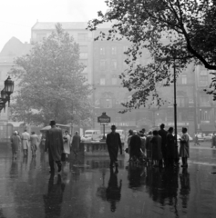 Magyarország, Budapest V., Vörösmarty tér, a felvétel a Gerbaud (Vörösmarty) cukrászda előtt készült. A Millenniumi Földalatti Vasút végállomásához vezető lejárat hátterében a 4-es számú ház látható., 1960, Faragó György, Budapest, járókelő, tükröződés, eső, Fortepan #260915