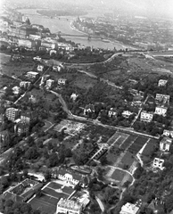 Magyarország, Budapest XI., légifotó a Gellérthegy déli lejtőjéről. Előtérben a Kertészeti és Szőlészeti Főiskola (később Szent István Egyetem, majd Magyar Agrár- és Élettudományi Egyetem, Budai Campus), háttérben a Széchenyi Lánchíd., 1963, MHSZ, légi felvétel, Budapest, Fortepan #26153