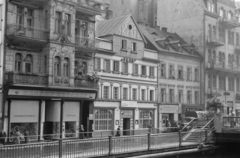 Csehország, Karlovy Vary, Vrídelní ulice a Teplá folyó partján, a.kép közepén a Dům Petr, tőle balra a Dům Rubín., 1956, Faragó György, építészet, üzletportál, cseh felirat, Csehszlovákia, Fortepan #261568