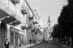 Csehország, Frantiskovy Lázne, Jiráskova ulice, szemben a Ruská ulice mellett a Szent Kereszt Felmagasztalása templom (Povýšení svatého Kříže)., 1956, Faragó György, utcakép, erkély, földút, utcaseprő, kovácsoltvas, Csehszlovákia, Fortepan #261611