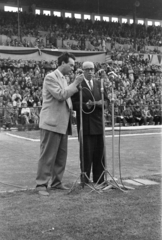 Magyarország, Budapest XIX., a Budapesti Honvéd SE újjáalakított pályájának megnyítója 1957.augusztus 24-én, a felvétel a Budapesti Honvéd – Tatabánya 1:2 mérközés alkalmával készült. Balra a mikrofonnál Szepesi György sportriporter., 1957, Faragó György, Budapest, nézőtér, mikrofon, riporter, stadion, Fortepan #261797