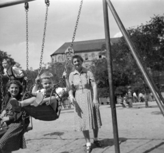 Magyarország, Budapest VII., Klauzál tér, háttérben a Kis Diófa utca sarkán álló Klauzál tér 16-os számú ház látható., 1954, Faragó György, hinta, játszótér, Budapest, képarány: négyzetes, Fortepan #261928