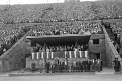 Magyarország, Népstadion, Budapest XIV., 1957. szeptember 22. Magyarország - Szovjetunió 1:2, barátságos válogatott labdarúgó-mérkőzés. A mérkőzés előtt rövid ünnepség zajlott. A díszpáholyban megjelentek – többek között – Dobi István, Marosán György, Münnich Ferenc, Biszku Béla és szovjet vendégeik. A kép előterében, a monitor előtt Szepesi György sportriporter., 1957, Faragó György, Budapest, nézőtér, dísztribün, politikus, zászló, Fortepan #261946