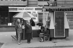 Magyarország, Budapest XI., az Ünnepi könyvhét kiadványait árusító pavilon a Bartók Béla út 51. számú ház előtt. Bal szélen Kodolányi Gyula költő, műfordító, irodalomtörténész., 1967, Gyulai Gaál Krisztián, Budapest, olvasás, napernyő, plakát, pavilon, fodrászat, könyvvásár, Fortepan #262233