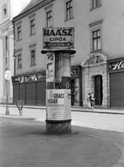 Magyarország, Győr, Széchenyi tér, hátterében a Loyolai Szent Ignác bencés templom és a rendház., 1938, Nagy István, Nagy József, plakát, hirdetőoszlop, szemetes, cipőbolt, Fortepan #264251