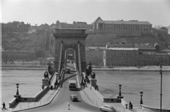 Magyarország, Budapest V.,Budapest I., kilátás a Széchenyi István (Roosevelt) tér felől a Széchenyi Lánchíd és a Duna felé. Jobbra fenn a budai Várban a Várszínház és az egykori Karmelita kolostor épülete., 1954, Horváth József, Budapest, híd, Turul-szobor, csibilámpa, palota, kőoroszlán, látkép, Fortepan #265660