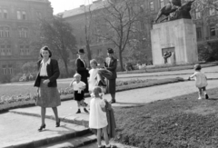 Magyarország, Budapest II., a mai Gyóni Géza (ekkor névtelen) tér a Margit híd budai hídfőjénél. Jobbra a lengyel Przemyśli 2-es tüzérezred hősi emlékműve, Sződy Szilárd (aki Przemysl várában teljesített szolgálatot főhadnagyként) szobrász- és éremművész alkotása (1932)., 1943, Ábrahám Katalin és László, Budapest, kalap, kosztüm, masni, kislány, család, Fortepan #266670