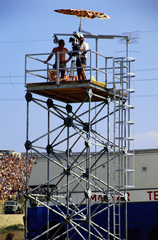 Magyarország, Hungaroring, Mogyoród, a felvétel a Formula-1 első magyar nagydíjon készült, az MTV kameraállása., 1986, Glósz András, autóverseny, Forma-1, állvány, tévékamera, napernyő, Fortepan #268540