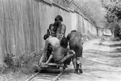 Magyarország, Budapest XV., Károlyi Sándor (Ifjúgárda) út, a Rákospalotai Lánynevelő Intézet udvara. A felvétel a Bűn című négyrészes televíziós dokumentumfilm-sorozat forgatásakor készült., 1982, Kanyó Béla, Budapest, filmforgatás, háttal, betolás, filmkamera, fahrt-sín, fahrtkocsi, szögesdrót, Fortepan #268684