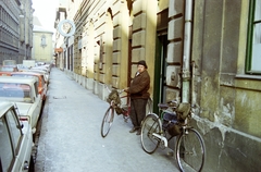 Hungary, Budapest VII., Akácfa utca, munkába induló kéményseprő, az 57. számú házban a Fővárosi Ké­ményseprő és Tüzelés­­technikai Szolgáltató Vál­lalat irodája és öltözője előtt. Távolban a Király (Majakovszkij) utcánál az Avilai nagy Szent Teréz-templom (Terézvárosi templom) látható., 1983, Kanyó Béla, Budapest, chimney sweeper, bicycle, colorful, Fortepan #269134