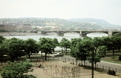 Magyarország, Budapest V., a mai Olimpia park területe, a Széchenyi rakpart a Balassi Bálint utca 9-11-ből nézve. Szemben a Margit híd és a Rózsadomb., 1967, Szilvási hagyaték, játszótér, Budapest, színes, Fortepan #270016