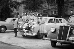 Magyarország, Margitsziget, Budapest, Margitszigeti Nagyszálló, parkoló autók a főbejárat előtt., 1954, Ladinek Viktor, Ford Customline, csoportkép, család, masni, lányok-járművek, autón ülni, amerikai gyártmány, rendszám, Lancia-márka, Ford-márka, Fortepan #273170