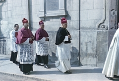 Magyarország, Veszprém, Vár (Tolbuhin) utca, a felvétel a Szent István ferences templom előtt készült. A templom kapuja mellett, a falon Ányos Pál pálos szerzetes, tanár, a magyar szentimentalizmus költészetének alakjának emléktáblája. Elől Badalik Bertalan veszprémi püspök halad a papszentelés helyszínére, a Szent Mihály-székesegyház felé., 1956, Hámori Gyula, körmenet, sapka, pap, emléktábla, színes, Fortepan #276210