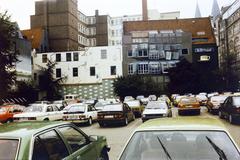 Germany, Bremen, Wachtstrasse és a Böttcherstrasse-i gépkocsiparkoló, szemben Jimmi D. Paesler
"Hervorragende Bremer Fenster" című alkotása (falfestmény) látható. Jobbra a Bremer Baumwollbörse épülete mögött a Bremer Dom tornyai látszanak., 1986, Csaba László örökösei, Best of, Ford-brand, Mercedes-brand, Fortepan #288598