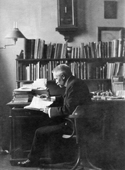 Romania,Transylvania, Cluj-Napoca, Cholnoky Jenő földrajztudós a Kolozsvári Tudományegyetem tanári szobájában., 1910, Cholnoky Tamás, celebrity, desk, reading, moustache, man, bookshelf, suit, wall clock, pendulum clock, Fortepan #29754