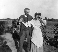 Hungary, Kecskemét, Cholnoky Jenő földrajztudós a Szikra gazdaság szőlészetében., 1910, Cholnoky Tamás, celebrity, jesting, moustache, fun, grape, man, apron, lady, suit, skirt, blouse, covering the face, posture, Fortepan #29757